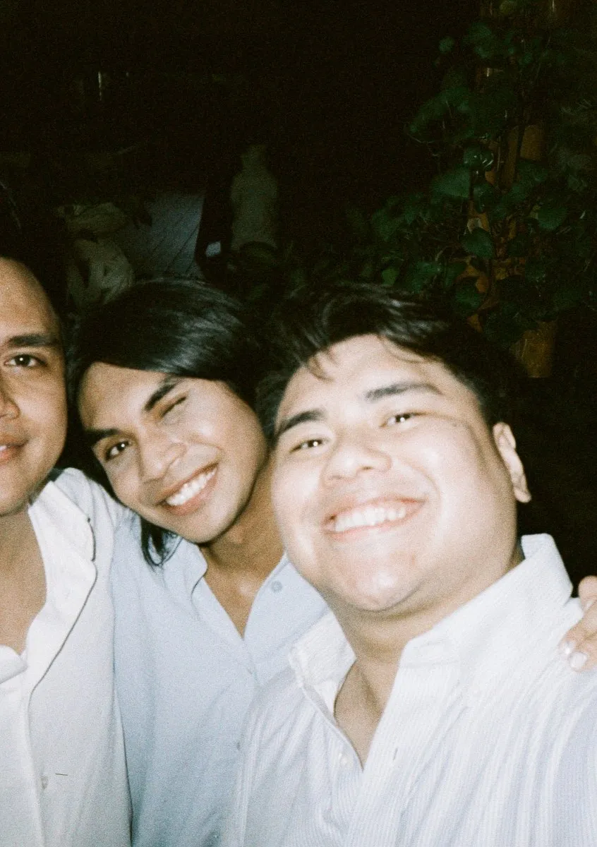 Three teammates squished together for a 35mm film portrait in Manila