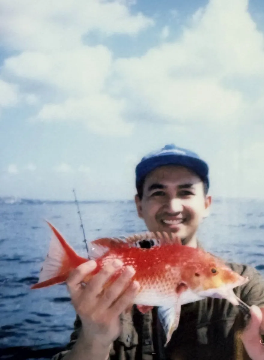 A teammate holding a red snapper on a fishing trip
