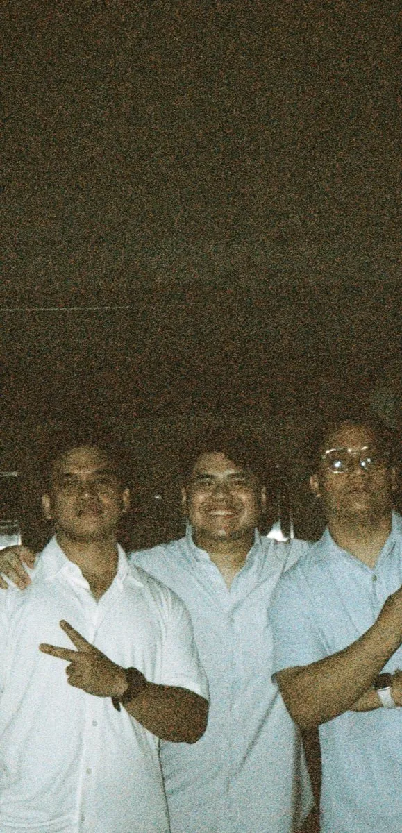 Three teammates throwing peace signs late at night, 35mm film