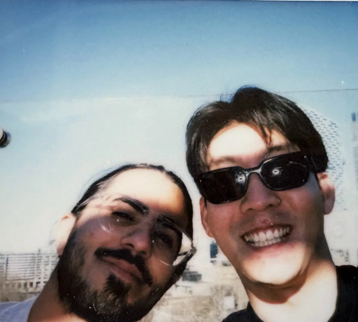 Close-up selfie of two teammates with the NY skyline behind